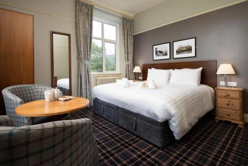 una habitación de hotel con una cama grande y una mesa en The Coniston Inn - The Inn Collection Group, en Coniston