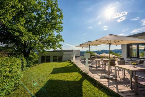 a patio with tables and chairs and an umbrella at Thula Wellnesshotel Bayerischer Wald in Lalling