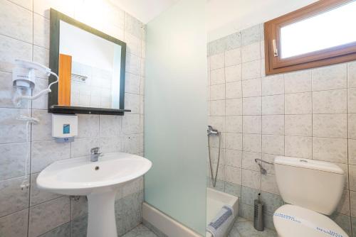 een badkamer met een wastafel, een toilet en een spiegel bij Hotel Erodios in Lithótopos