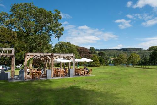 a picnic area with tables and umbrellas in a park at The Coniston Inn - The Inn Collection Group in Coniston