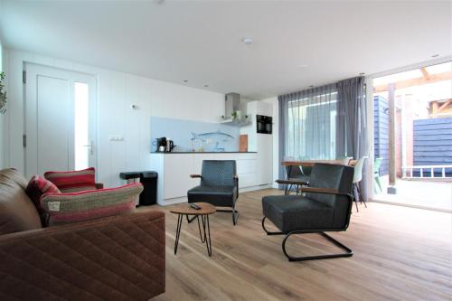 ein Wohnzimmer mit einem Sofa und Stühlen in der Unterkunft Beaufort in Egmond aan Zee