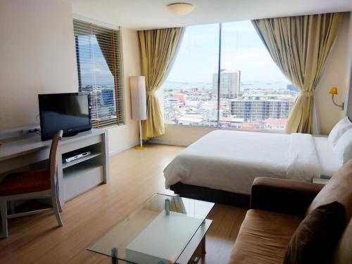um quarto de hotel com uma cama, um sofá e uma televisão em The City Hotel Sriracha by BBH Japan em Si Racha