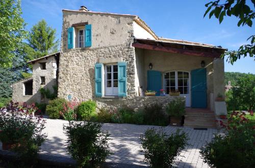 een klein stenen huis met blauwe deuren en ramen bij Les Demeures du Clos in Niozelles