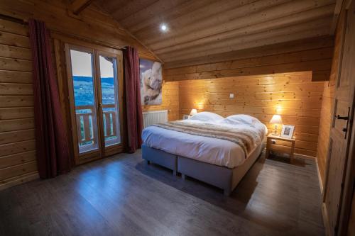 een slaapkamer met een bed en een groot raam bij Chalet Skadi in La Bresse