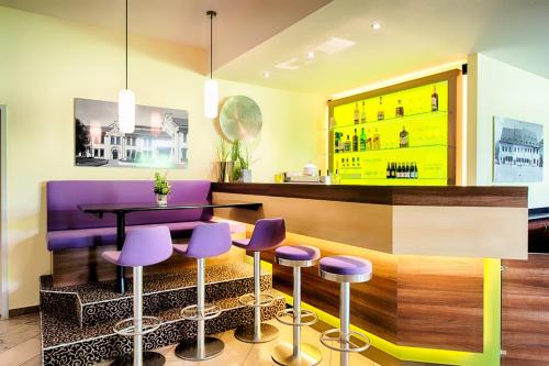 bar z fioletowymi stołkami i stołem w obiekcie ACHAT Hotel Zwickau w mieście Zwickau