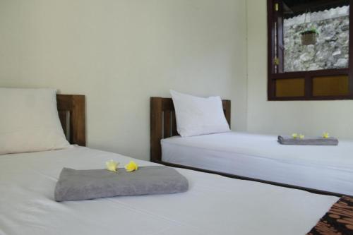 two beds in a room with yellow flowers on them at Omah Kebon Nitiprayan in Bantul