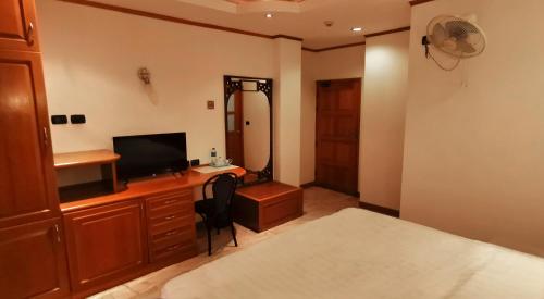 um quarto com uma secretária, uma televisão e uma cama em Max Residence em Pattaya Central