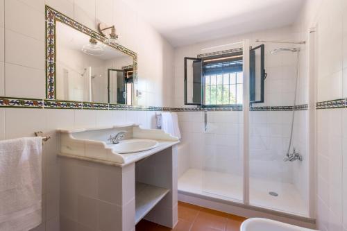 y baño blanco con lavabo y ducha. en Cortijo El Carmen Finca El Revuelo, en Constantina