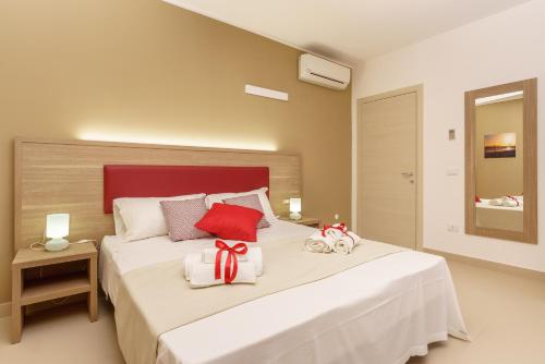 a bedroom with a large white bed with a red headboard at Travini Hotel Residence in Marsala