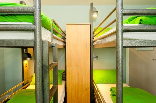 a room with four bunk beds with green sheets at YHA Stratford-Upon-Avon in Stratford-upon-Avon