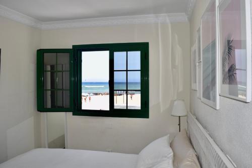 a bedroom with a bed and a window with a beach at Beachfront Bungalow Cotillo Lagos in Cotillo