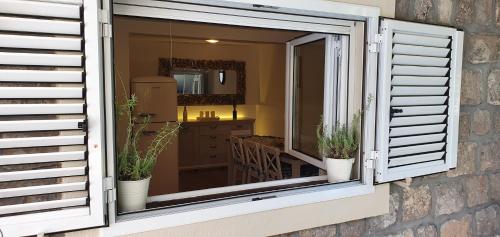 an open window with potted plants in a room at Villa Stella Rose in Lustica
