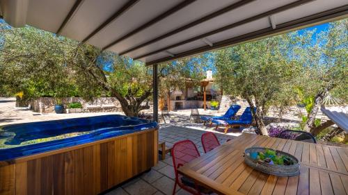 a patio with a wooden table and a swimming pool at Anthemion Suites and Villas in Nafplio