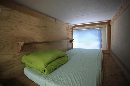 a small bedroom with a bed with a green pillow at Edo Tokyo Hostel in Tokyo