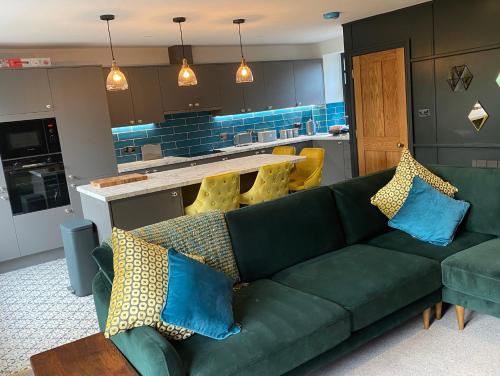 a living room with a green couch and a kitchen at Wuthering Heights in Sedbergh