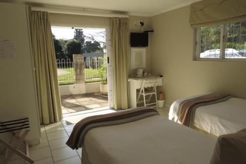 1 dormitorio con 2 camas y puerta a un patio en Avillahouse Guesthouse, en Durban