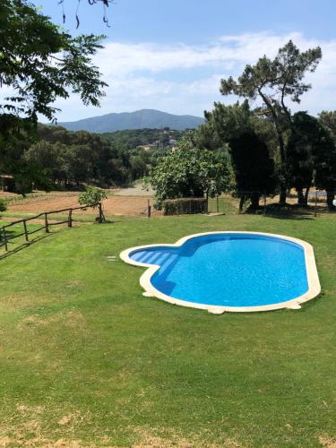 une grande piscine bleue dans une pelouse dans l'établissement LAS MIMOSAS MASBELL RURAL, à Tordera
