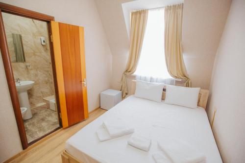 a bedroom with a white bed and a bathroom at Гостевой дом с геранью in Krasnodar