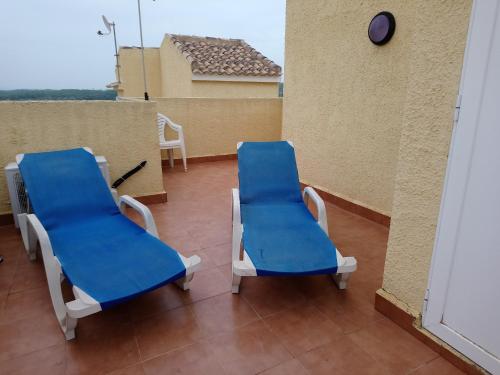 zwei blaue Stühle auf dem Balkon in der Unterkunft Tui Casa in Puerto Marino