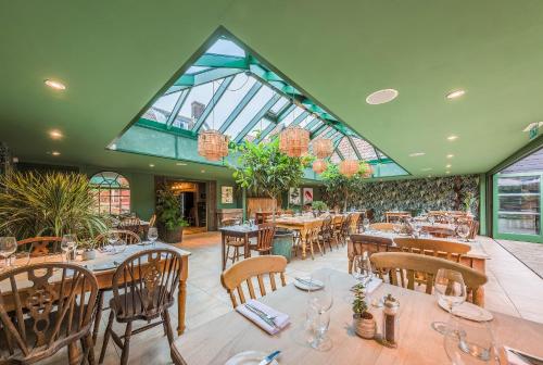 a restaurant with tables and chairs and a glass ceiling at The Westleton Crown in Westleton