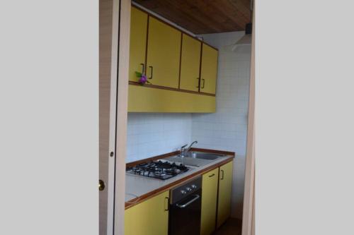 a kitchen with yellow cabinets and a sink and a stove at Chalet nel bosco in Borca di Cadore