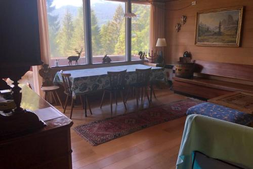 een woonkamer met een tafel en een groot raam bij Chalet nel bosco in Borca di Cadore