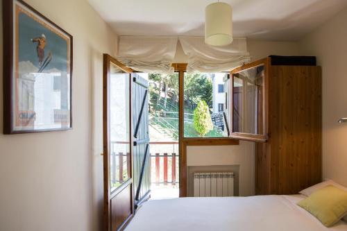 福米加尔Foratata By PIRINEOS360 Formigal - 3 dormitorios Y 2 baños的有一张床和一扇开着的窗户的卧室