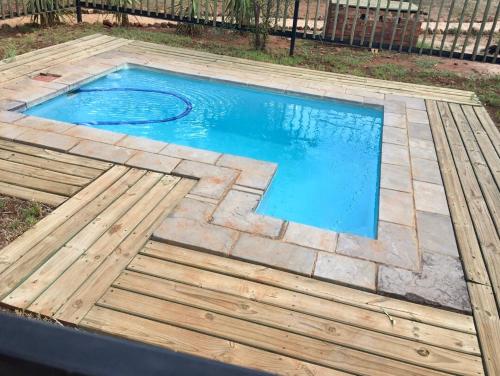 una pequeña piscina con terraza de madera y agua azul en Damascus Bush Lodge, en Hartbeespoort