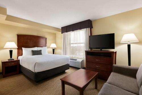 a hotel room with a bed and a flat screen tv at Days Inn & Suites by Wyndham Sherwood Park Edmonton in Sherwood Park