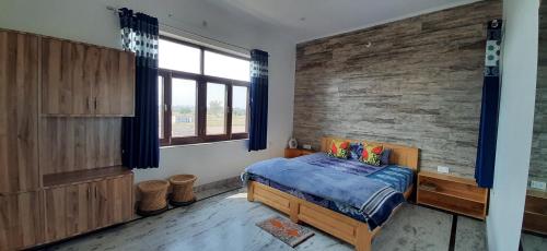 a bedroom with a bed and a brick wall at IbisHouse Farm Stay in Bharatpur