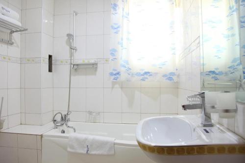 a white bathroom with a sink and a tub at Kyato Hotel in Kasanda