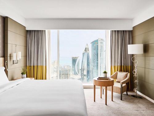 a hotel room with a bed and a desk and a window at Pullman Doha West Bay in Doha
