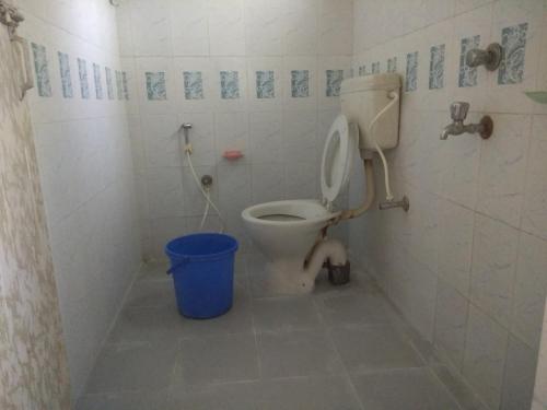a bathroom with a toilet and a blue bucket at Tarangamala Resort in Mandarmoni