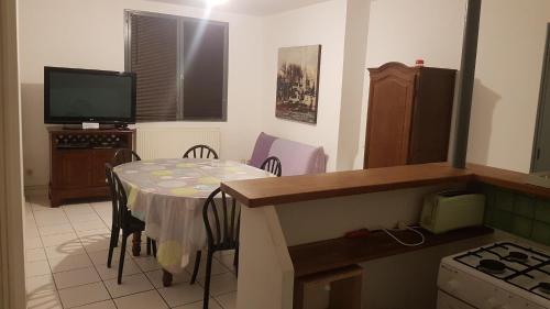 cocina con mesa con sillas y TV en appartement simple entier avec cour pour 2 a 7 personnes, en Château-Gontier