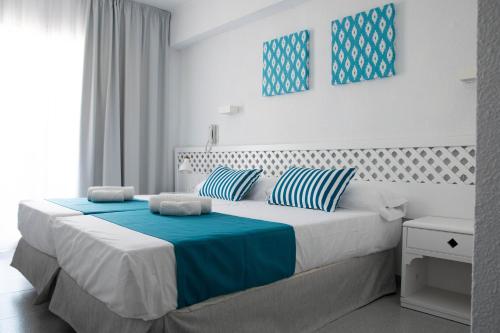 a bedroom with a large bed with blue and white pillows at BLUESEA Mediodia in El Arenal