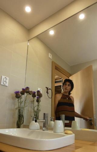 a woman standing in front of a bathroom mirror at Casa da Laja - Casas de Villar- Rural Experience in Vilar de Amargo