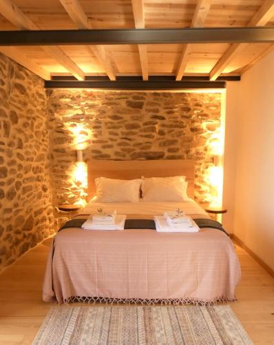 a bedroom with a bed with a stone wall at Casa da Laja - Casas de Villar- Rural Experience in Vilar de Amargo