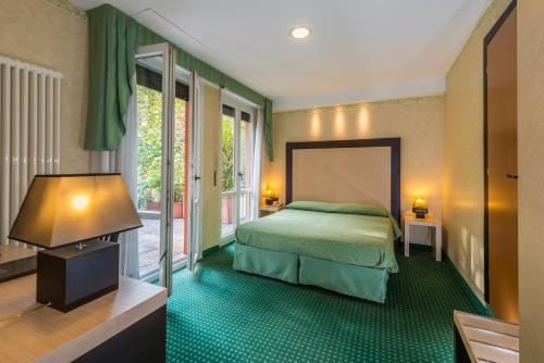 una camera con un letto verde e una grande finestra di Hotel Don Abbondio a Lecco
