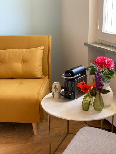 a living room with a couch and a table with flowers at Allegro Holiday in Nizza Monferrato