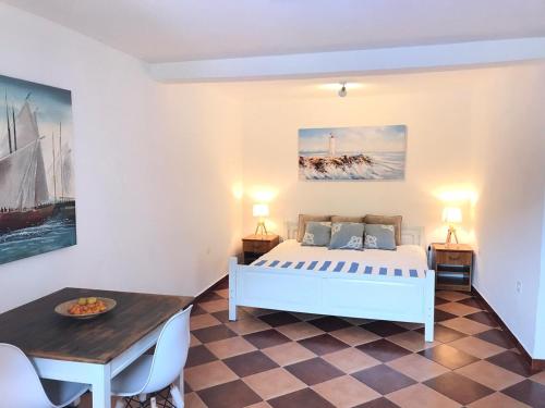 Villa Stella Rose في لوستيكا: غرفة نوم بسرير ابيض وطاولة