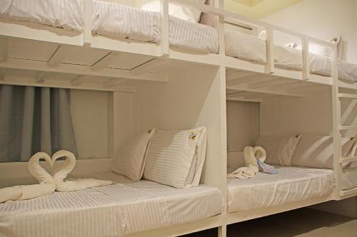 two white bunk beds with swan pillows and towels at Layang Layang Home in El Nido