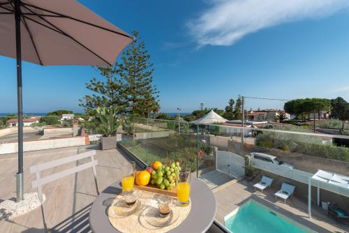 a table with a bowl of fruit on top of a balcony at Villa Livia - IsulaTravel in Fontane Bianche