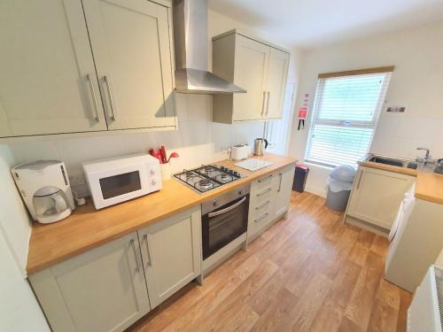 a kitchen with white cabinets and a white microwave at Bassett Flat with 2 Bedrooms and Superfast Wi-Fi in Sittingbourne