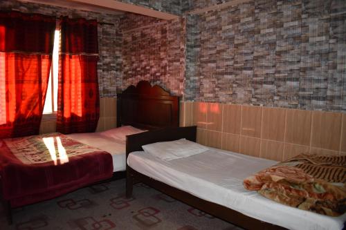 マリーにあるMusyari Guest Houseのレンガの壁と赤いカーテンが備わる客室のベッド2台