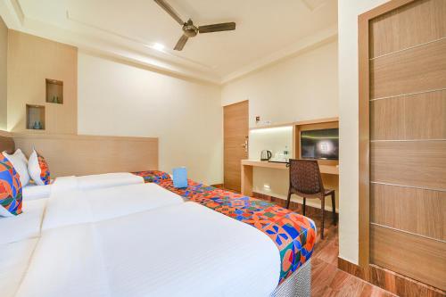 a hotel room with a large bed and a desk at Nestlay Rooms Vanagaram in Chennai
