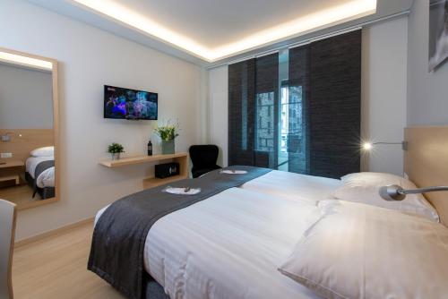 a bedroom with a large white bed and a window at Hotel des Alpes in Geneva