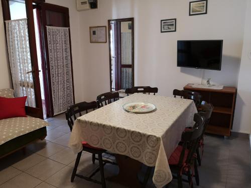 uma sala de jantar com uma mesa com cadeiras e uma televisão em Queen beach apartments Nin Sabunike - Green street I em Nin