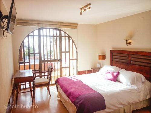 1 dormitorio con cama, mesa y ventana en Hotel Huasco en Huasco