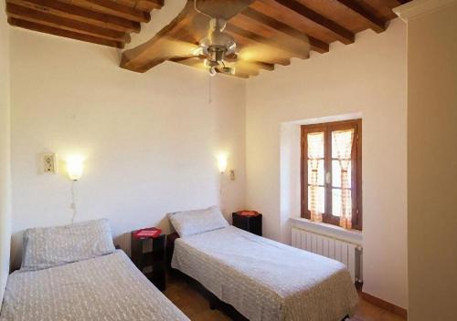 sypialnia z 2 łóżkami i wentylatorem sufitowym w obiekcie Tuscan Farmhouse with 7 Apartments for max 30 persons w mieście Montecastelli