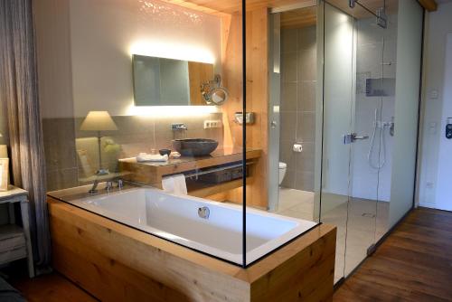 uma casa de banho com uma banheira grande e uma cabina de duche em vidro. em Wellnessgarten-Hotel em Waging am See
